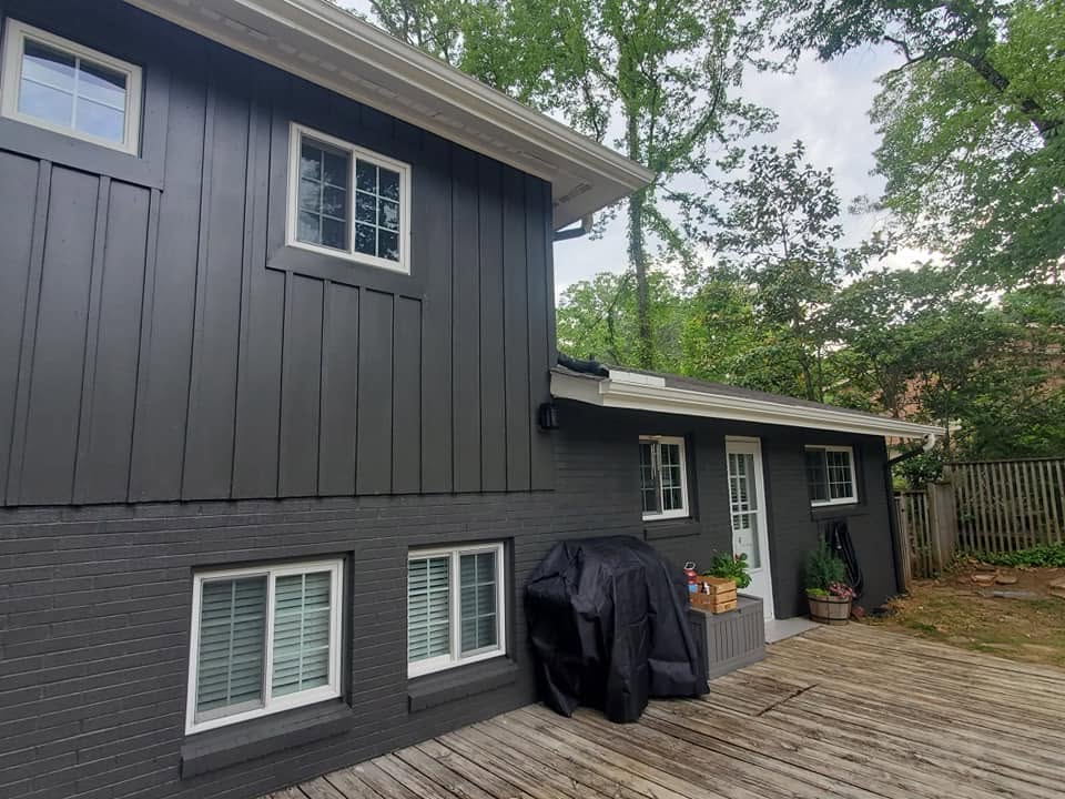Two-story home with freshly painted black exterior siding and a wood deck, completed by Paint Pro